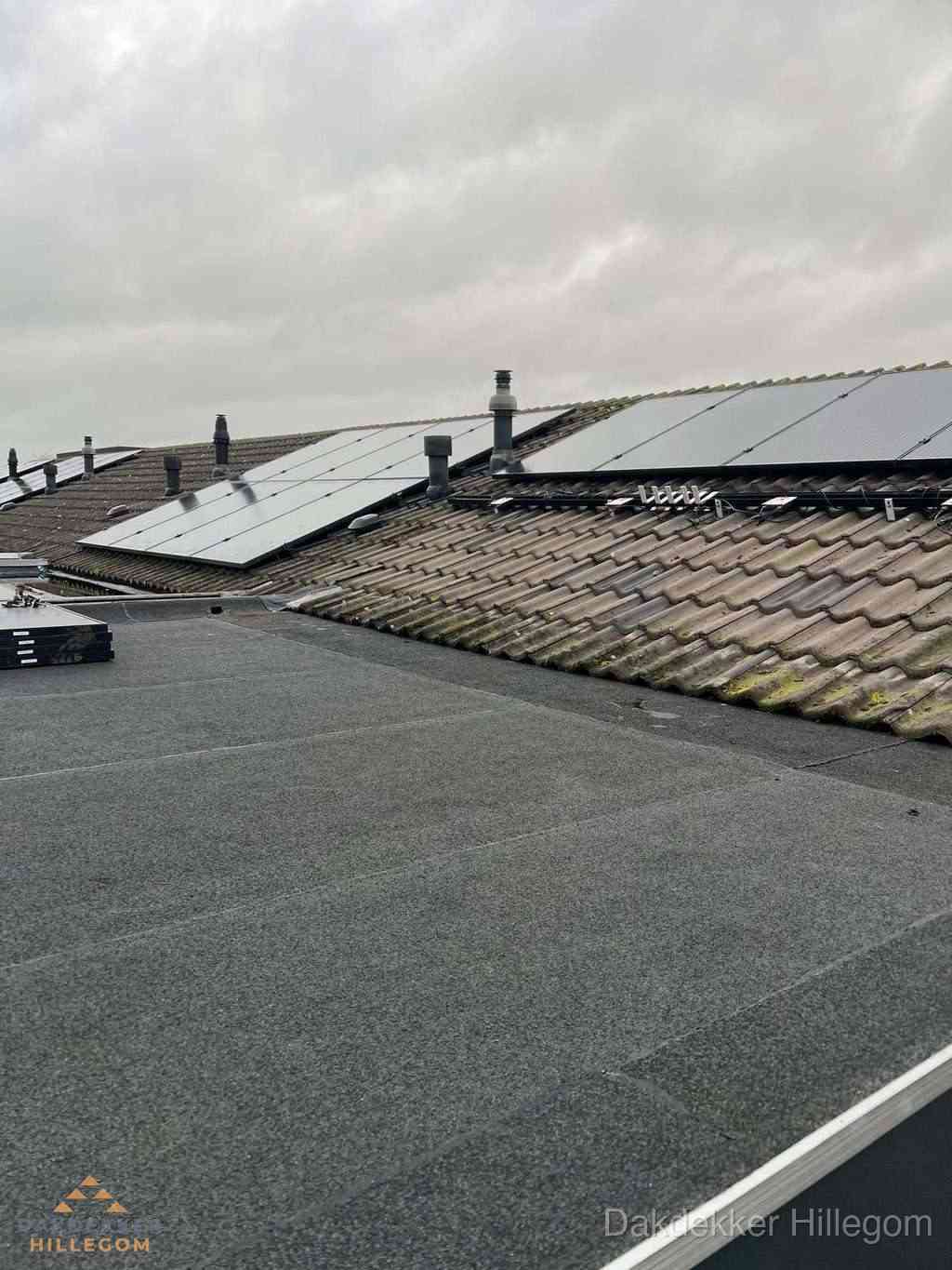 Plat dak inspectie met bitumen bedekking naast schuin pannendak in Hillegom
