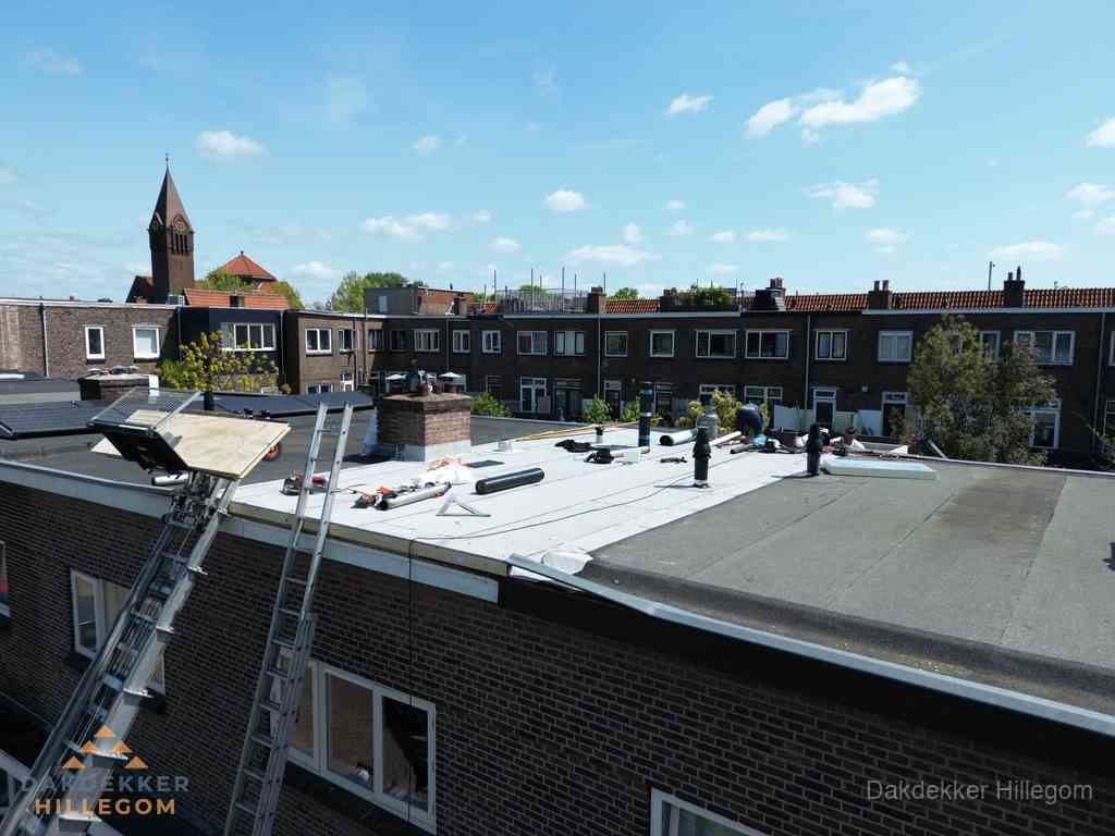 Dakdekkers aan het werk op plat dak in Hillegom