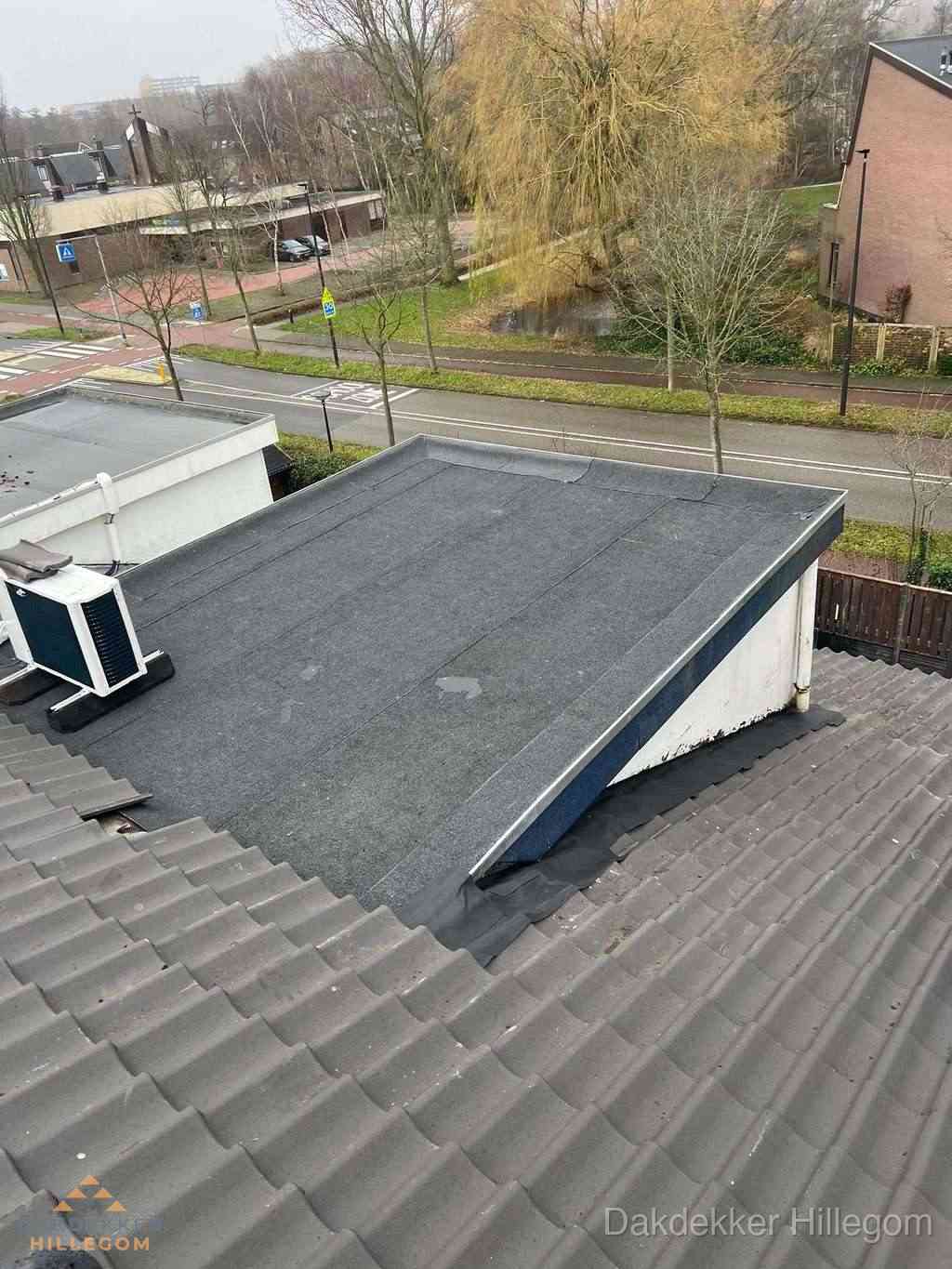 Plat dak met bitumen dakbedekking naast schuin pannendak in Hillegom